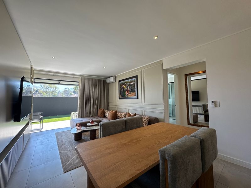 Modern open-plan living and dining area featuring tiled floors, decorative wall paneling, recessed lighting, and seamless access to an outdoor patio space.