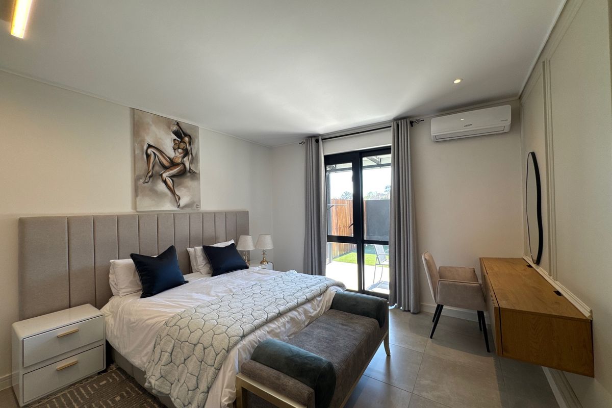A well-maintained bedroom featuring tiled flooring, wall-mounted air conditioning, and direct access to an outdoor area through a sliding glass door.