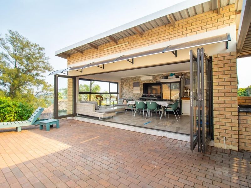 Spacious covered patio featuring large bi-fold doors, brick construction, and a stone feature wall, seamlessly connecting indoor and outdoor living areas.