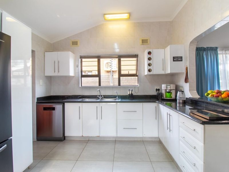 A functional kitchen featuring white cabinetry, dark granite countertops, tiled backsplash, and integrated dishwasher, offering a clean and practical workspace.