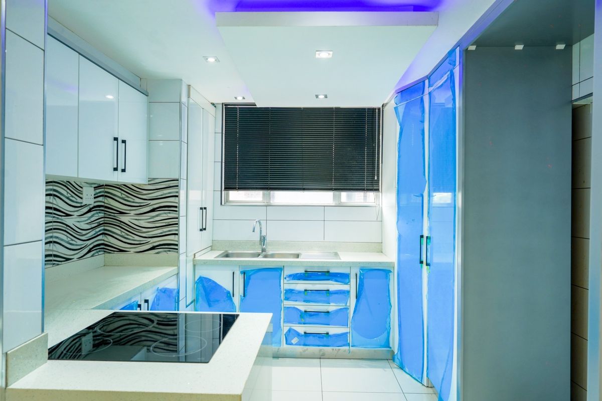 Modern kitchen featuring white high-gloss cabinetry, stone countertops, integrated electric hob, and recessed lighting. The space appears newly installed and ready for use.