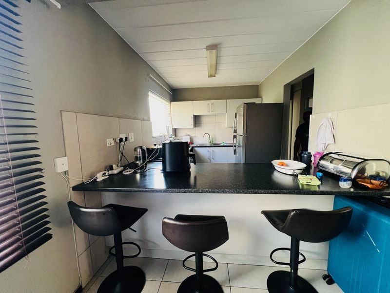 A functional kitchen featuring a breakfast bar, ample cabinetry, tiled backsplash, and a stainless steel sink, providing a practical layout for daily use.