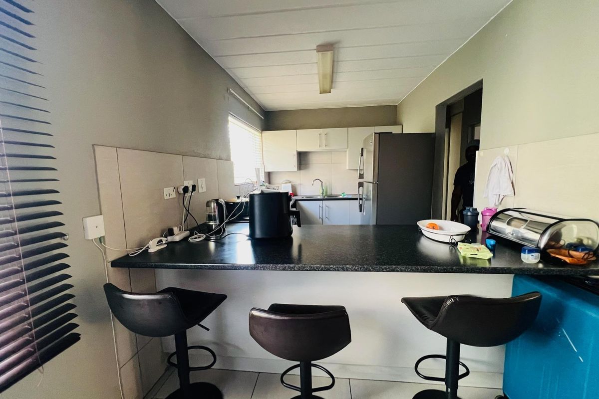 A functional kitchen featuring a breakfast bar, ample cabinetry, tiled backsplash, and a stainless steel sink, providing a practical layout for daily use.