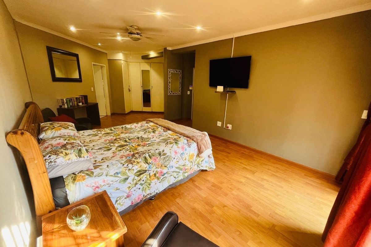 Spacious bedroom featuring laminate flooring, recessed ceiling lighting, a ceiling fan, and built-in storage cupboards.