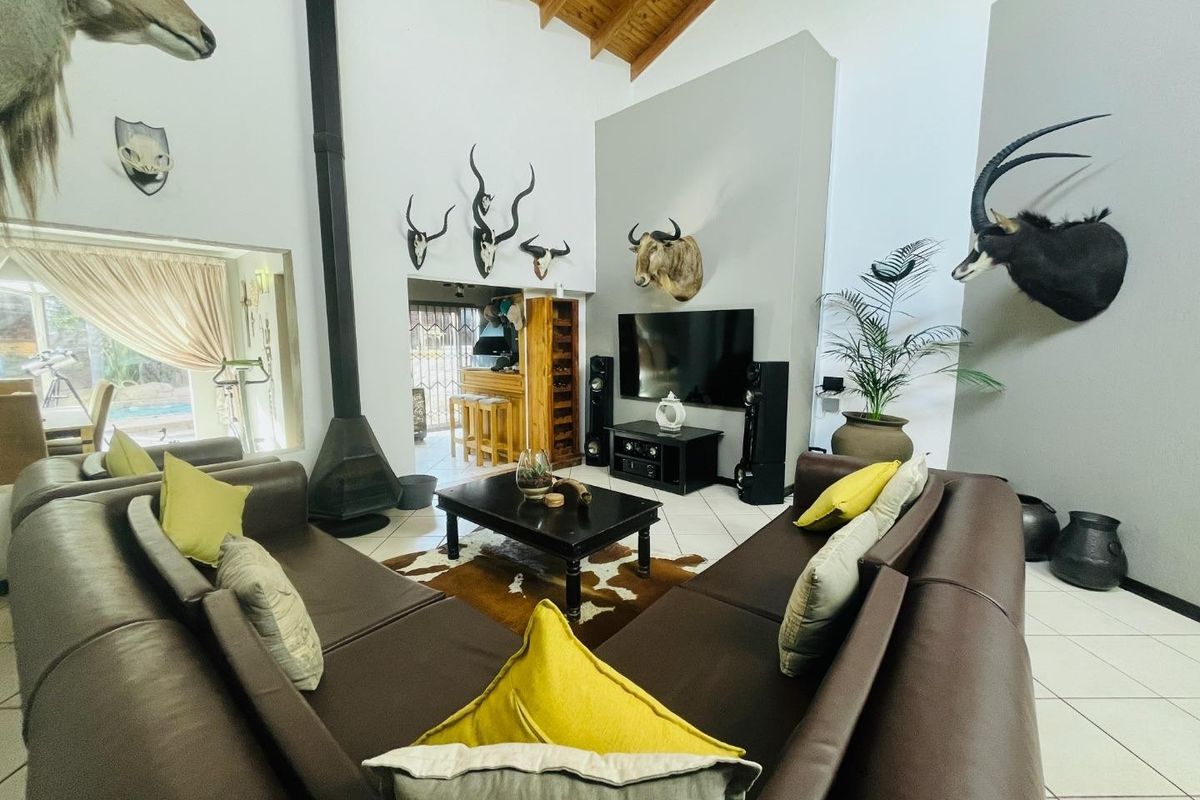 Spacious living room featuring a high vaulted timber ceiling, tiled flooring, and a prominent freestanding fireplace, creating a warm and inviting atmosphere.