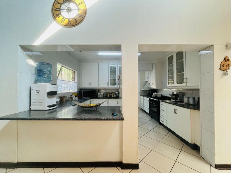 A functional kitchen featuring white cabinetry, dark granite countertops, tiled flooring, and a built-in oven, offering a practical layout with ample storage space.