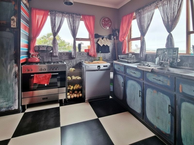 A kitchen featuring a gas stove, double sink, and tiled splashback, with a distinctive checkerboard floor and distressed-finish cabinetry.
