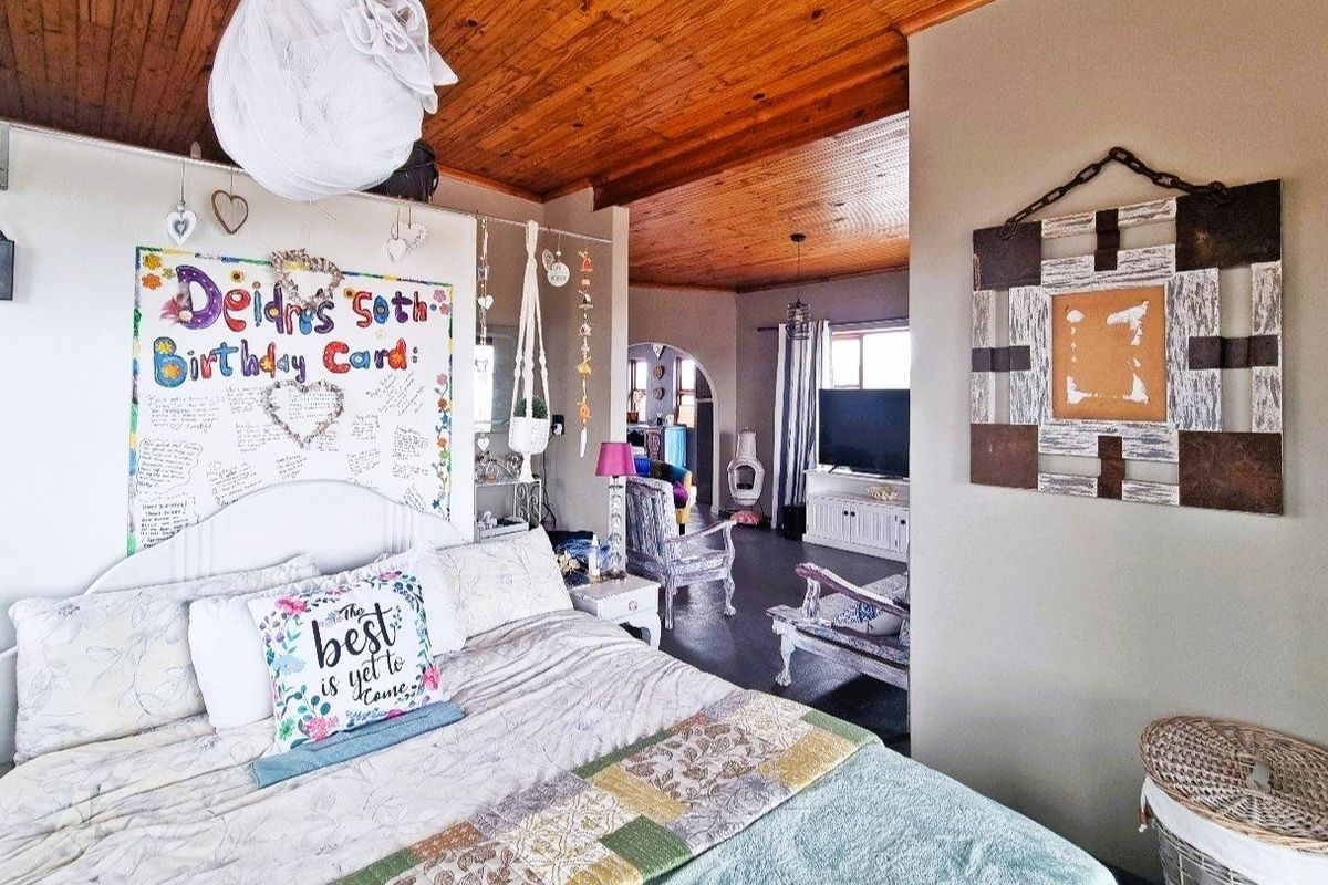 A bedroom featuring a warm timber tongue and groove ceiling, with an open layout leading into an adjacent living area.