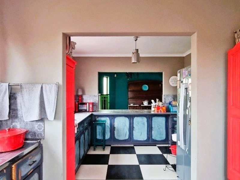 A kitchen featuring a distinctive checkered floor, built-in cabinetry with a tiled backsplash, and a pass-through window connecting to an adjacent space.