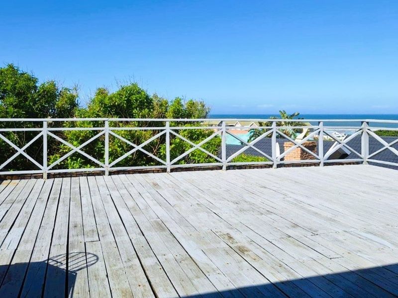 Spacious elevated timber deck featuring a classic cross-pattern balustrade and expansive ocean views, offering a perfect setting for outdoor relaxation.