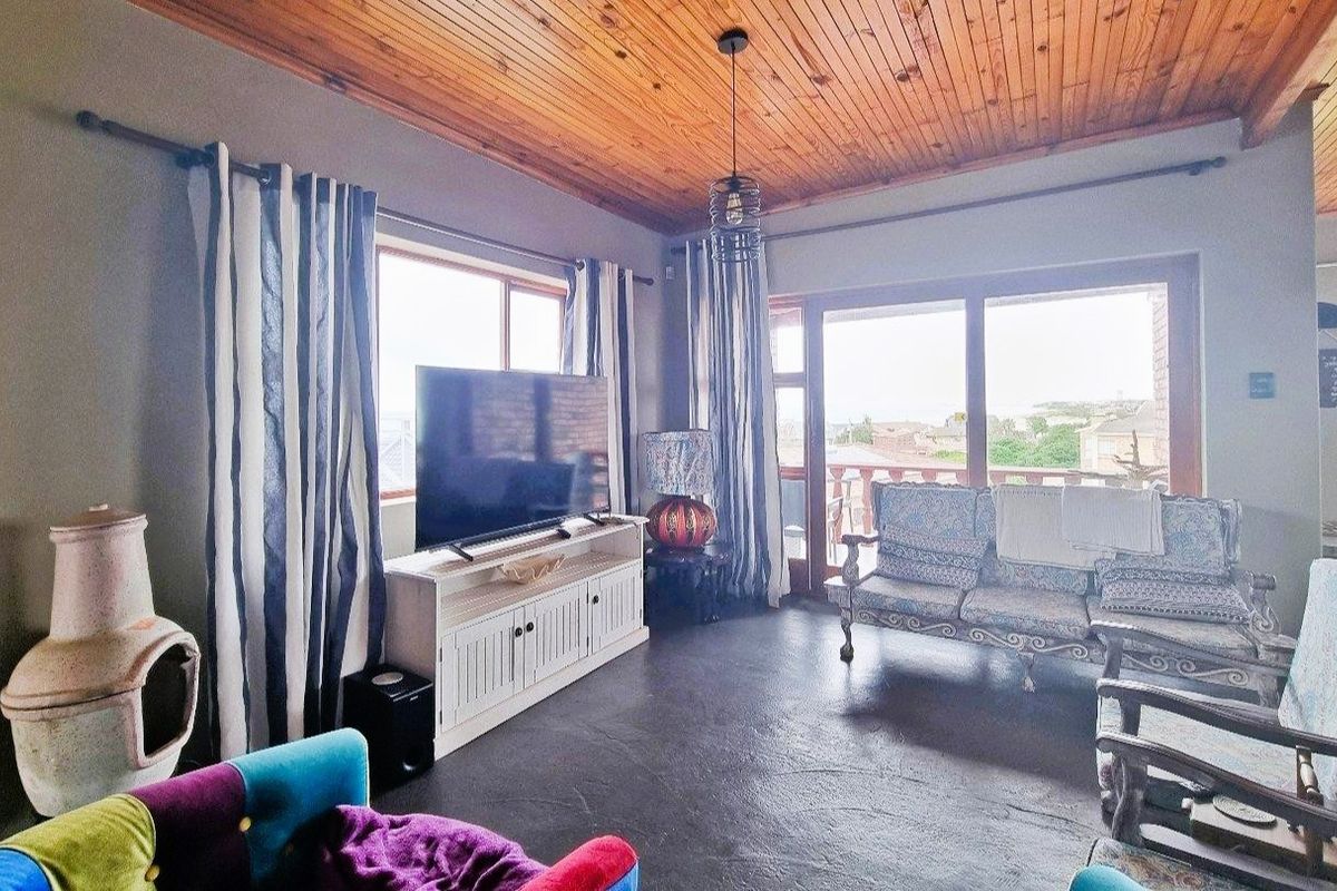 Spacious living room featuring a warm timber tongue and groove ceiling, large windows, and sliding glass doors that provide natural light and outdoor access.