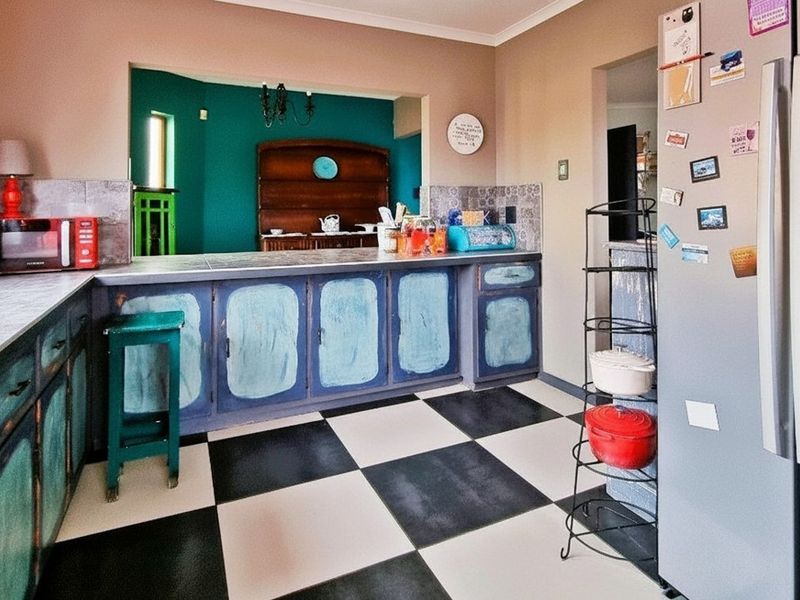 A kitchen featuring checkerboard flooring, laminate countertops, and a pass-through window connecting to the adjacent living space.