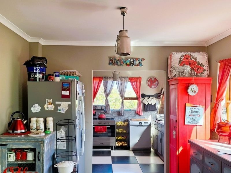 A kitchen featuring checkerboard flooring, built-in cabinetry, and a functional layout with a separate scullery or prep area visible through the doorway.