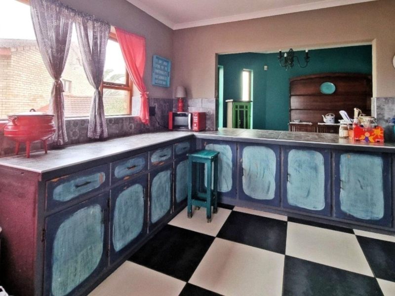 A kitchen featuring checkered floor tiles, tiled countertops, and built-in cabinetry with a dated finish, offering potential for a modern renovation.
