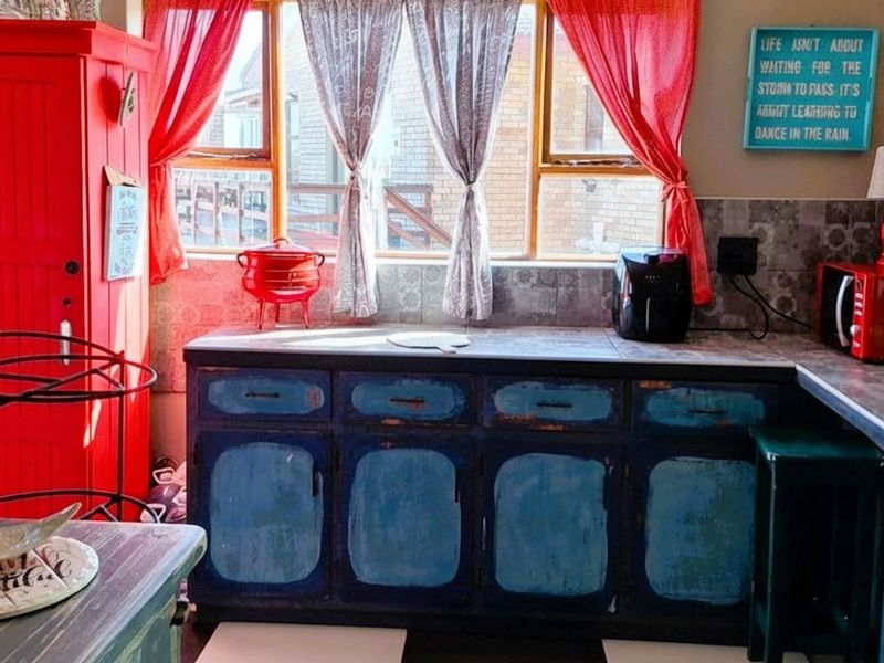 A kitchen area featuring dated cabinetry with a worn finish, tiled backsplash, and laminate countertops, providing a functional but aged workspace.