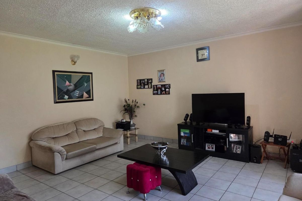 A spacious living room featuring neutral wall tones, tiled flooring, and a textured ceiling, providing a functional and comfortable living space.