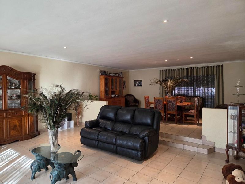 Spacious open-plan living and dining area featuring tiled flooring, recessed downlighting, and a split-level layout connecting the two zones.