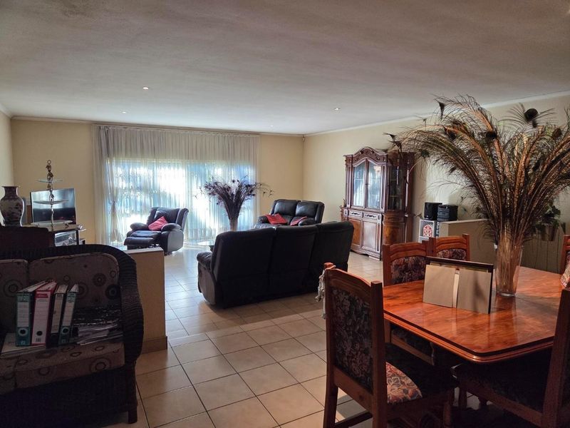 Spacious open-plan living and dining area featuring neutral tiled flooring, recessed lighting, and large sliding glass doors providing natural light.