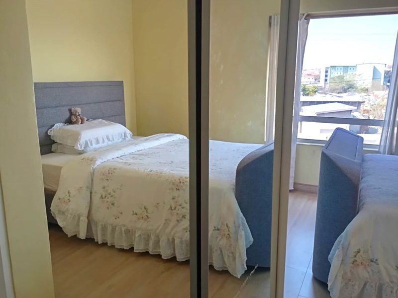 A bedroom featuring laminate flooring and a built-in mirrored wardrobe, offering natural light and a view through the window.