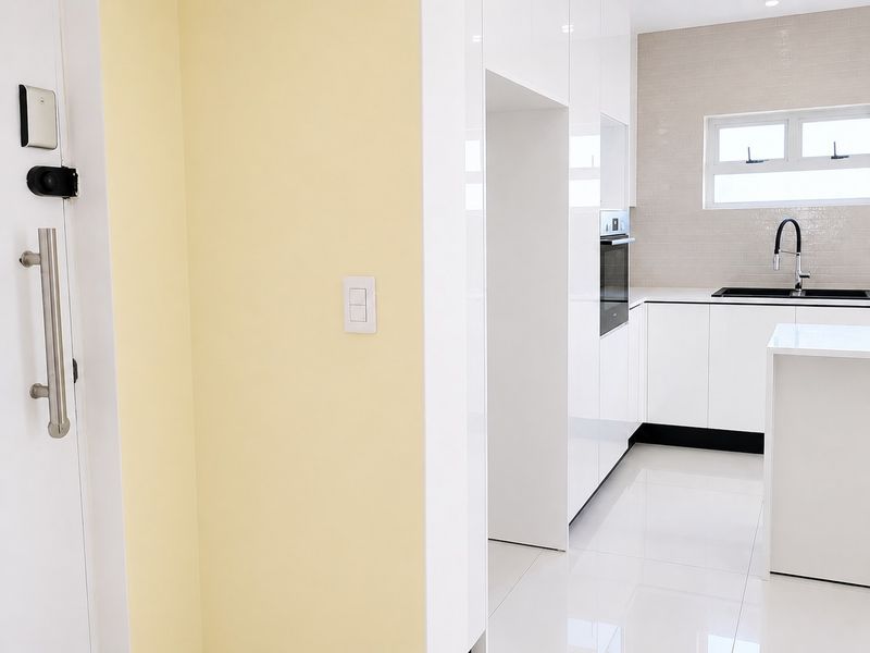 Modern kitchen featuring sleek white cabinetry, subway tile backsplash, built-in oven, and high-gloss tiled flooring in a clean, minimalist design.