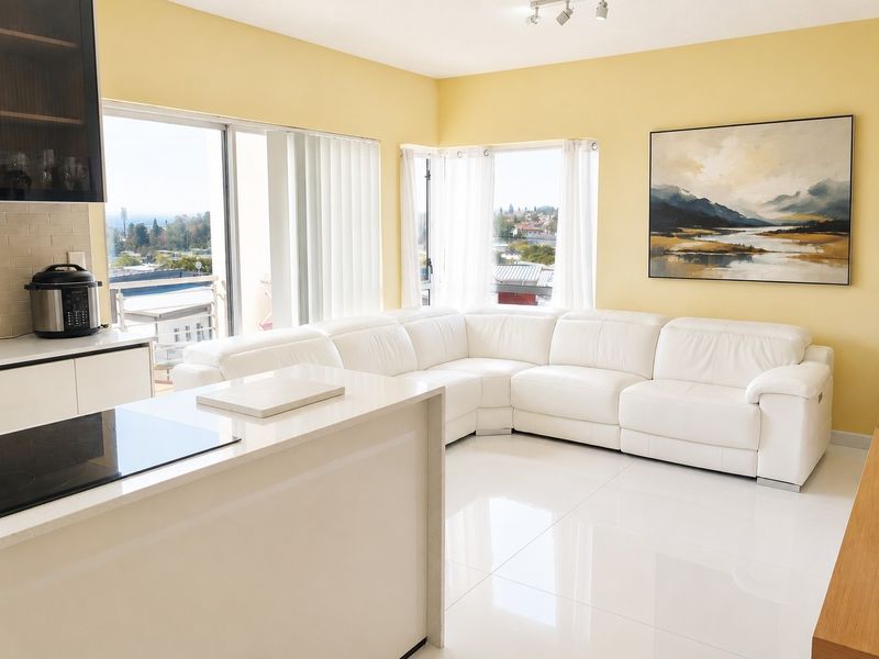 Bright open-plan living area featuring a modern kitchen with a central island, sleek cabinetry, and large windows offering expansive views.