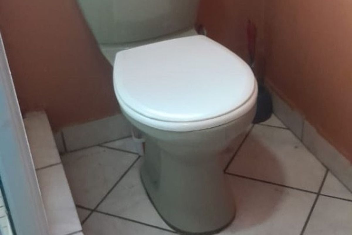 A functional bathroom space featuring a standard toilet, tiled flooring, and a window for natural light.