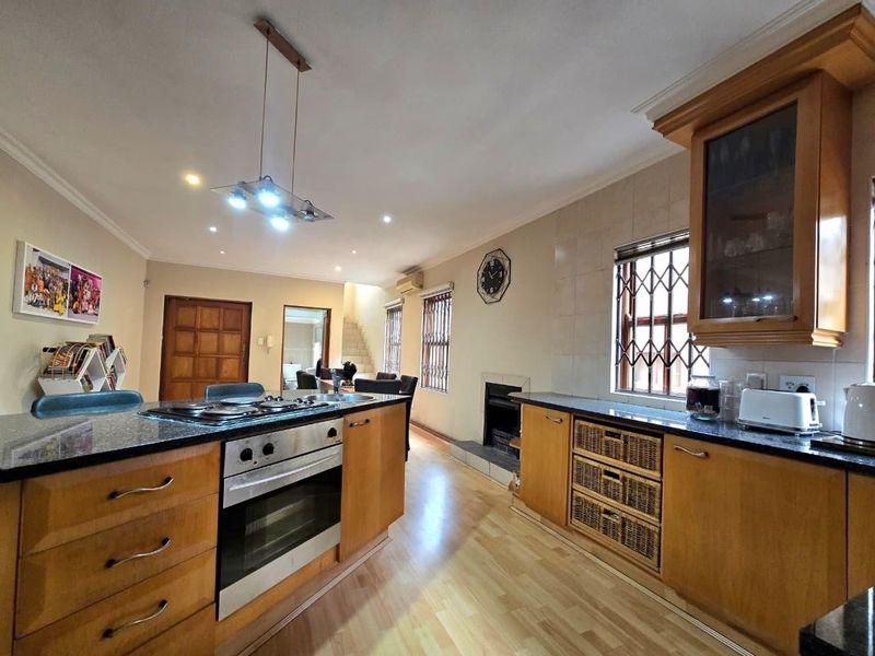 Spacious open-plan kitchen and living area featuring wooden cabinetry, granite countertops, a built-in oven, gas hob, and a cozy fireplace.