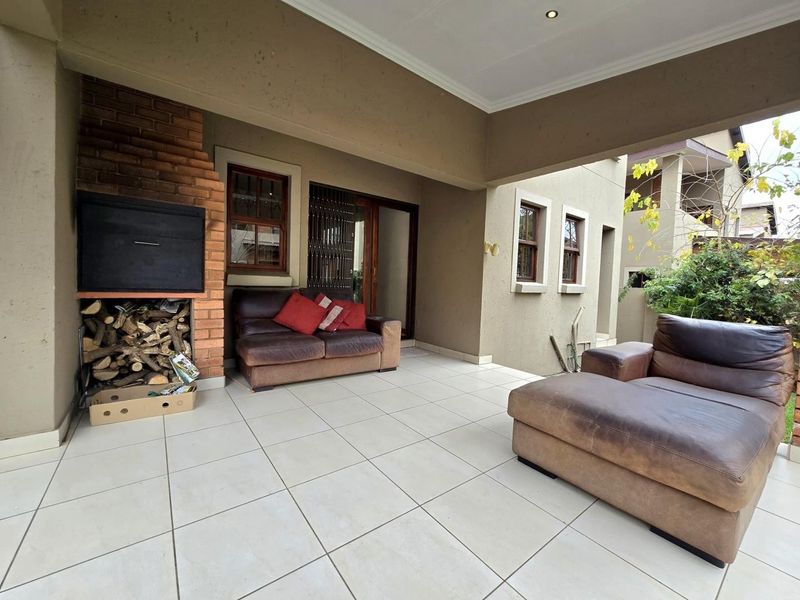 Covered patio area featuring a built-in brick braai, tiled flooring, and recessed lighting, providing a functional outdoor entertainment space.