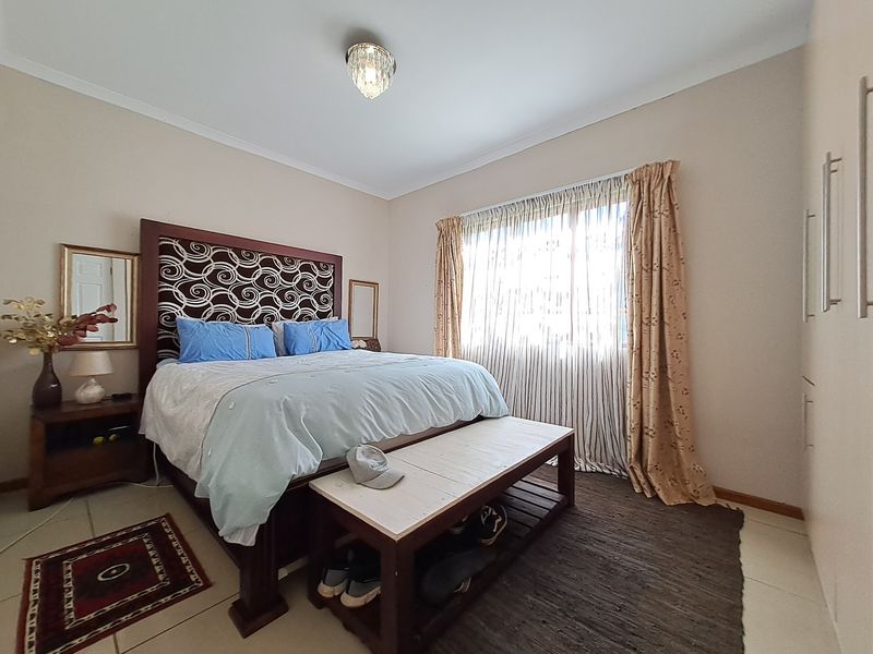 A well-maintained bedroom featuring tiled flooring, built-in cupboards, and a central ceiling light fixture, offering a comfortable and functional living space.