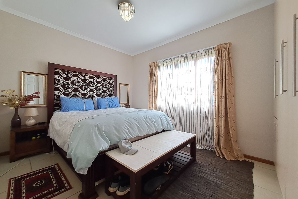 A well-maintained bedroom featuring tiled flooring, built-in cupboards, and a central ceiling light fixture, offering a comfortable and functional living space.