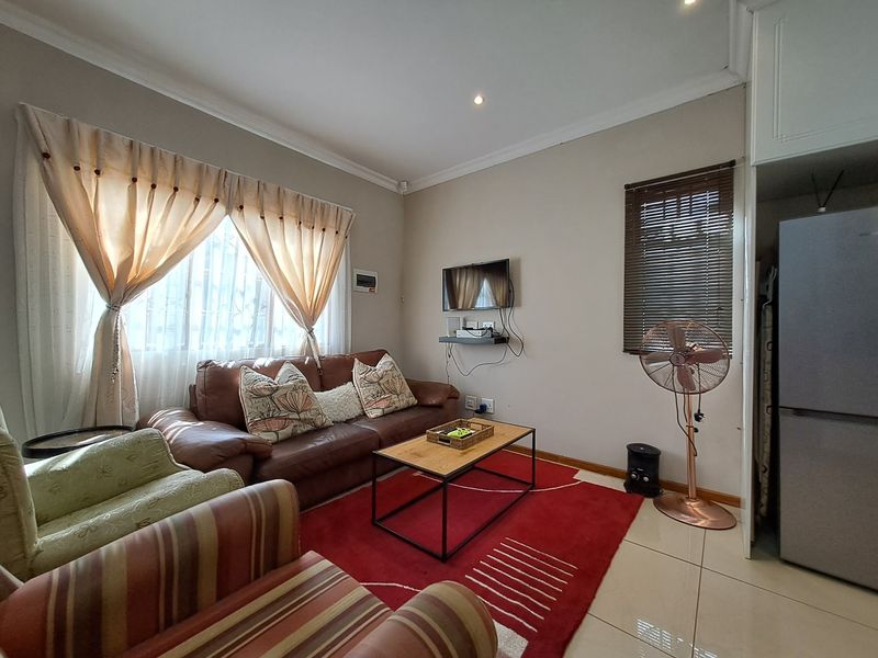 A functional living room featuring tiled flooring, recessed downlighting, and built-in cabinetry, providing a comfortable and practical space for relaxation.