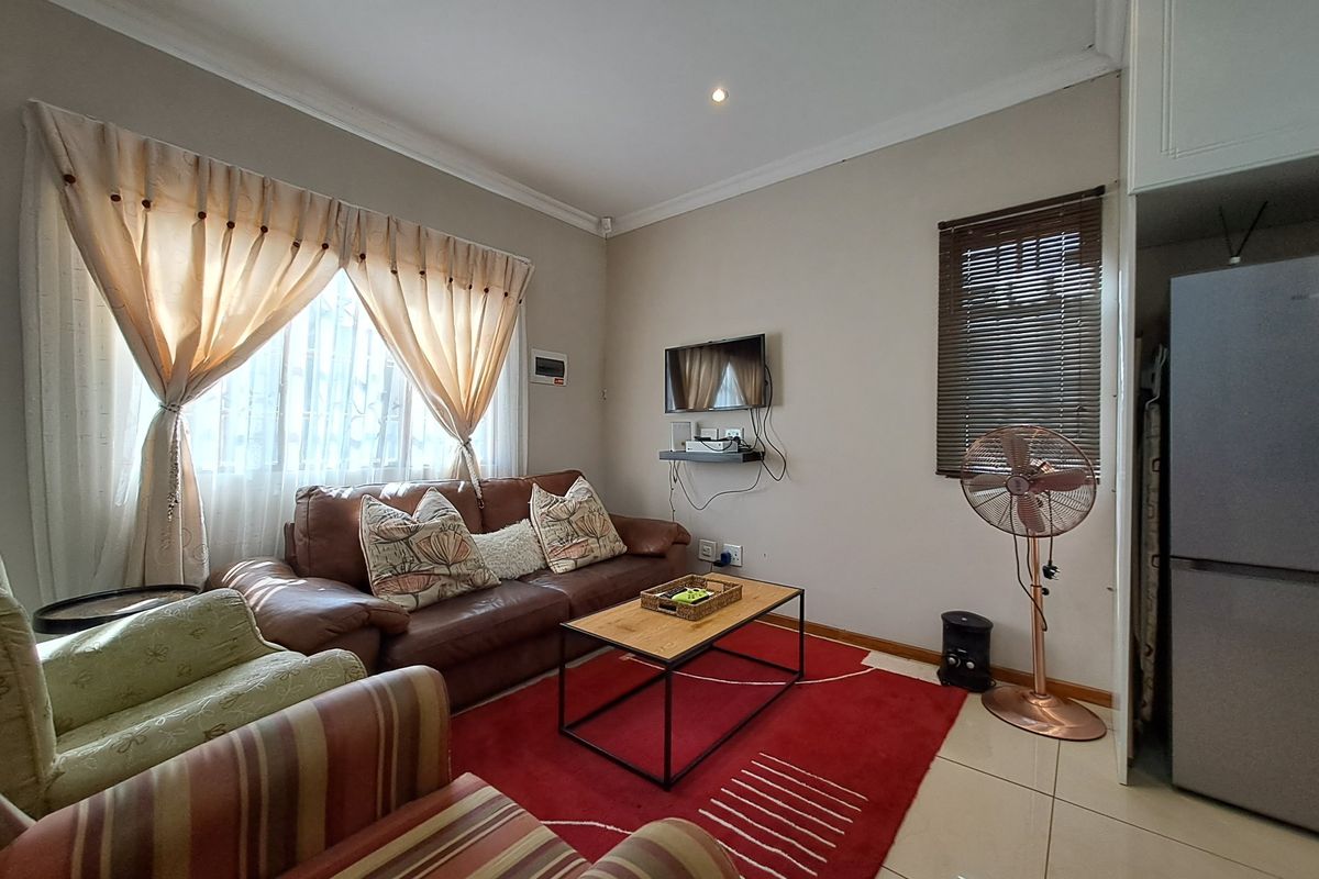A functional living room featuring tiled flooring, recessed downlighting, and built-in cabinetry, providing a comfortable and practical space for relaxation.