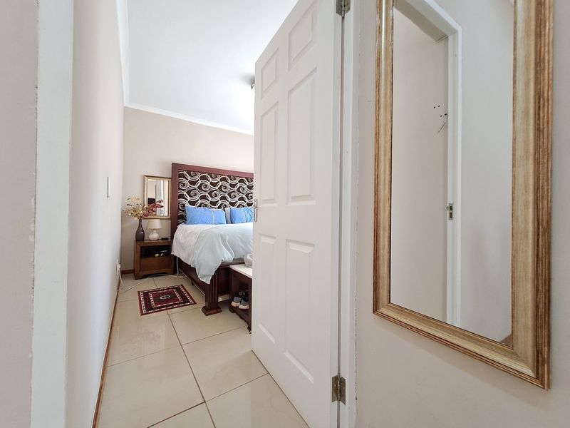 A view into a bedroom featuring tiled flooring and a panel door, showing a well-maintained interior space.