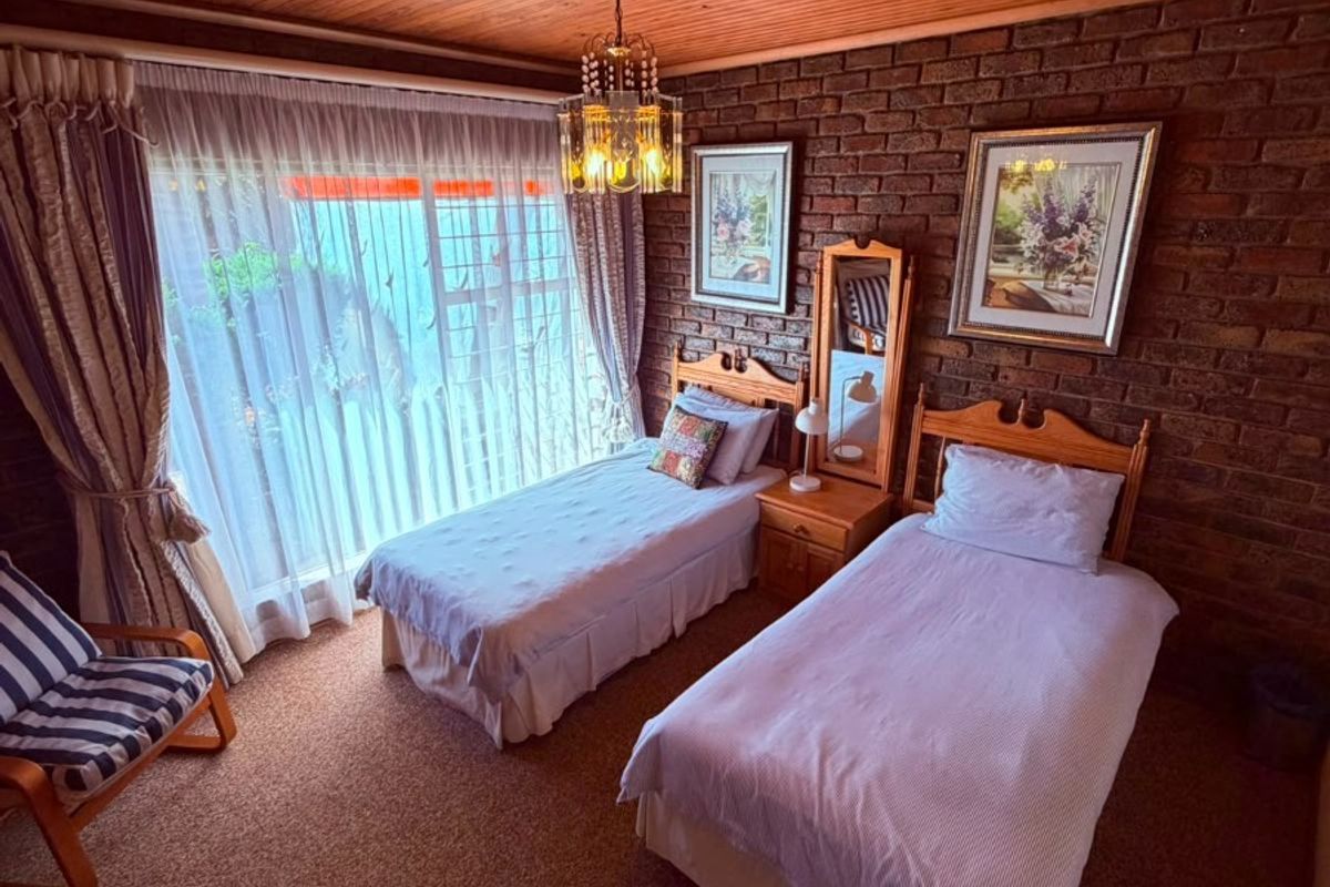 A bedroom featuring a timber ceiling, exposed brick wall, and sliding door access to the exterior.