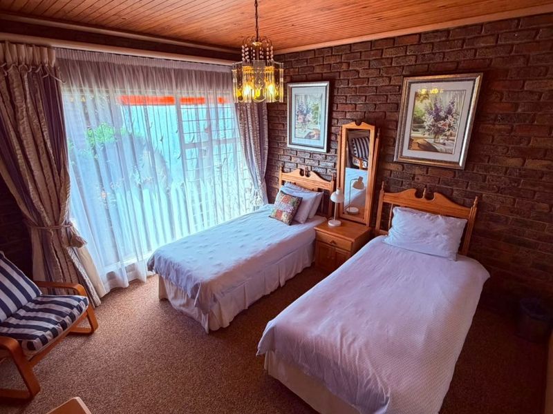 A bedroom featuring a timber ceiling, exposed brick wall, and sliding door access to the exterior.