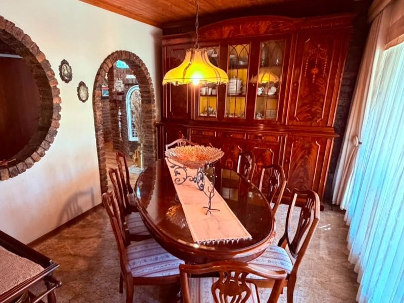 A traditional dining room featuring a warm timber tongue and groove ceiling, distinctive brick archways, and a circular brick wall feature.