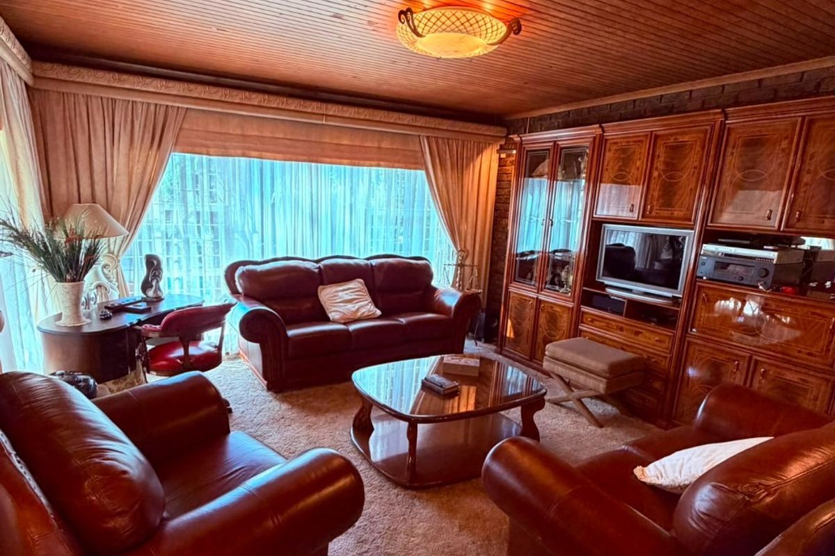 A traditional living room featuring a timber-clad ceiling, wall-to-wall built-in cabinetry, and carpeted flooring, offering a classic and cozy atmosphere.