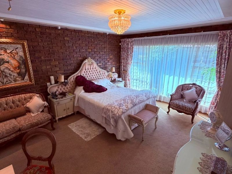 Spacious bedroom featuring an exposed brick feature wall, tongue and groove ceiling, and large sliding glass doors providing ample natural light.