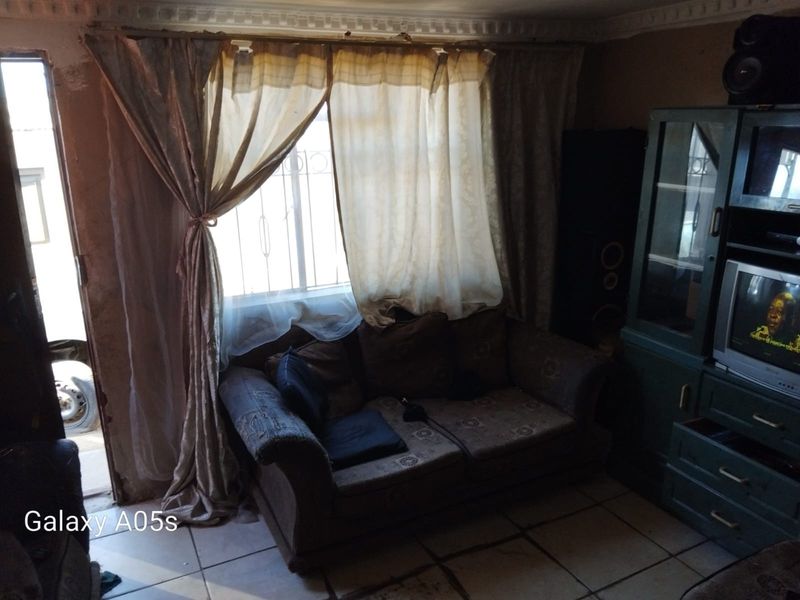 A living room area featuring tiled flooring and a security gate, requiring cosmetic updates to improve the overall aesthetic and condition.