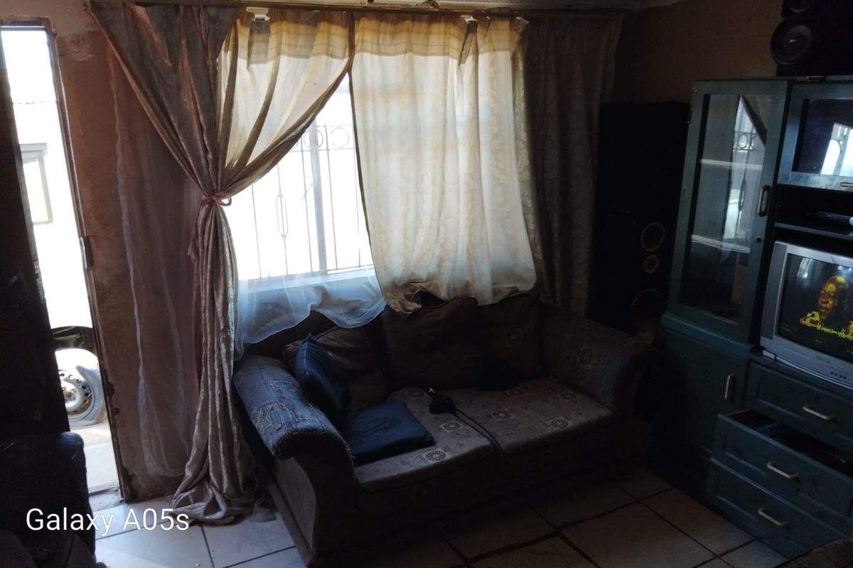 A living room area featuring tiled flooring and a security gate, requiring cosmetic updates to improve the overall aesthetic and condition.