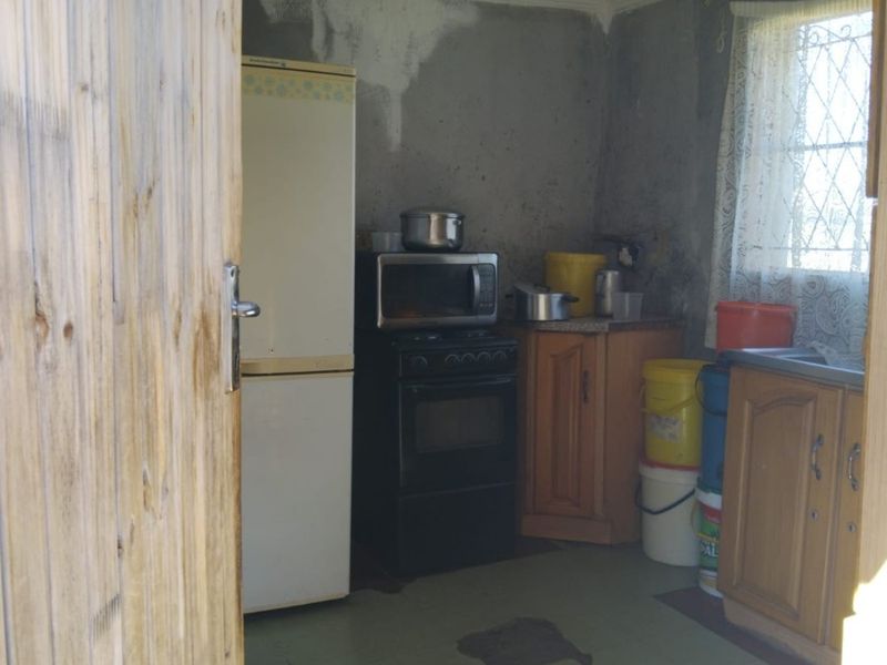 A small kitchen area featuring basic cabinetry and a sink, requiring significant cosmetic updates and wall repairs to improve the overall condition.