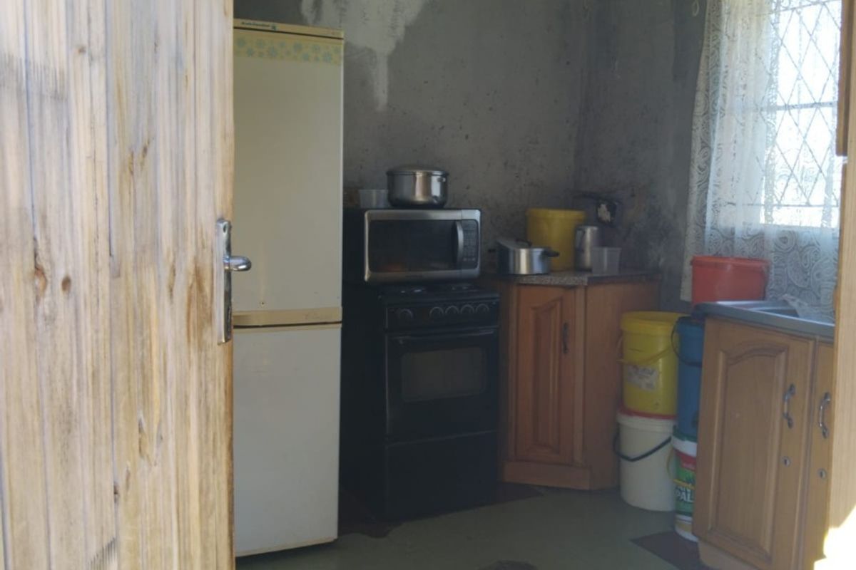 A small kitchen area featuring basic cabinetry and a sink, requiring significant cosmetic updates and wall repairs to improve the overall condition.