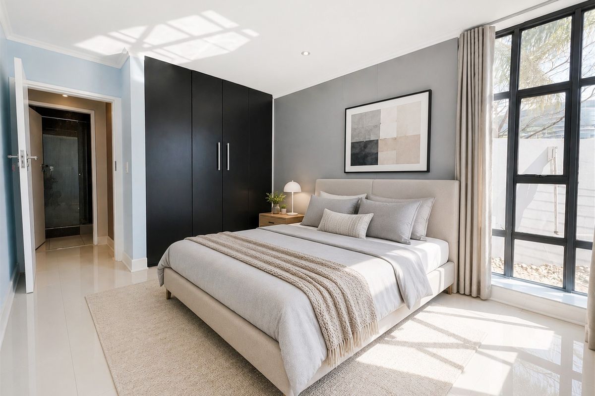Modern bedroom featuring sleek black built-in cupboards, large windows providing natural light, and neutral tiled flooring in a well-maintained apartment setting.