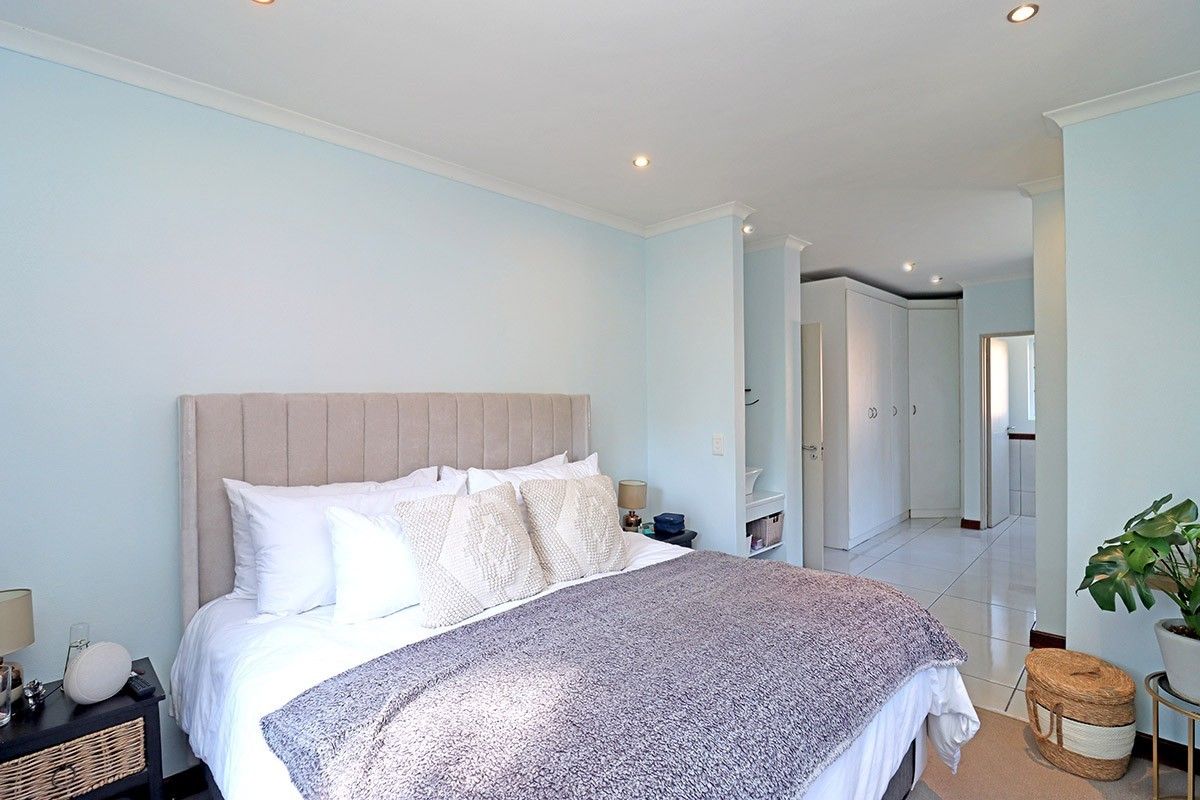 Spacious bedroom featuring neutral walls, tiled flooring, recessed downlighting, and ample built-in cupboard storage.