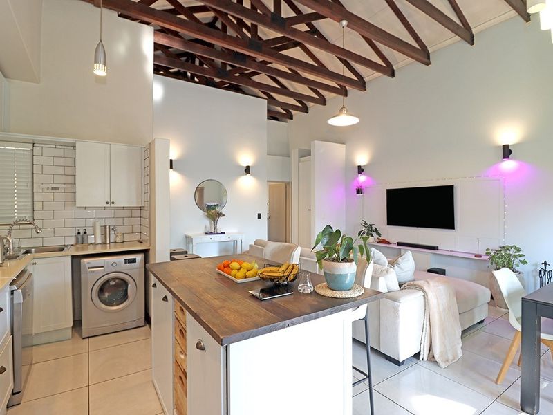 Spacious open-plan living area featuring exposed timber roof trusses, a modern kitchen with subway tile backsplash, and a functional kitchen island.