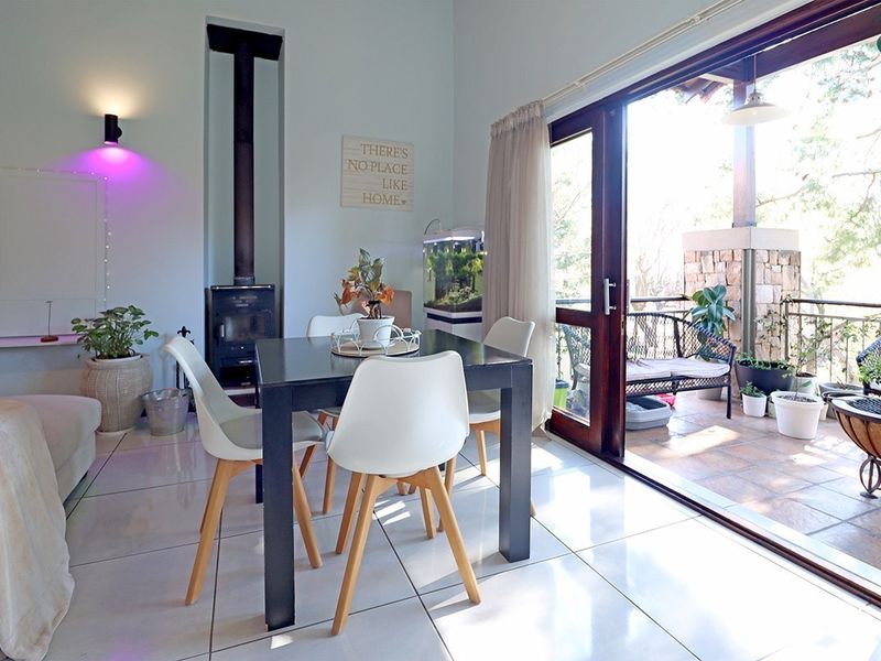 Open-plan living area featuring tiled flooring, a built-in wood-burning fireplace, and large sliding glass doors providing seamless access to the outdoor patio.