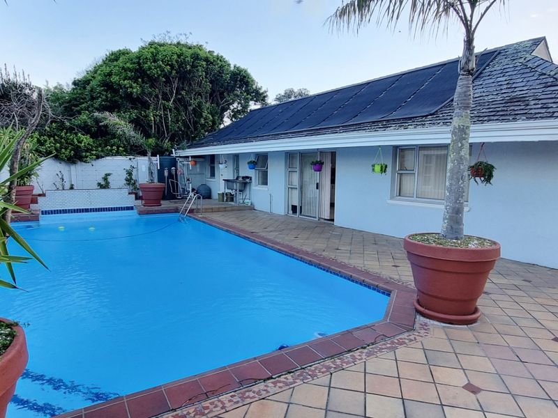 Outdoor pool area featuring a tiled patio, swimming pool with solar heating panels, and direct access to the cottage via sliding glass doors.