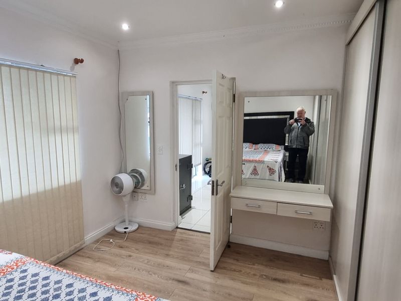 A well-maintained bedroom featuring laminate flooring, built-in wardrobes, and recessed lighting, offering a clean and functional living space.