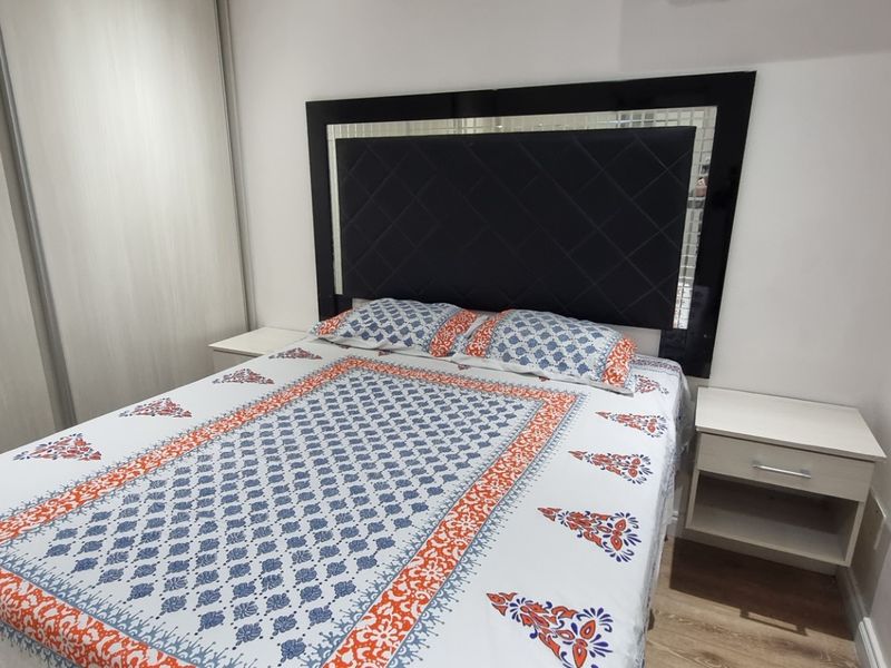 A well-maintained bedroom featuring light-toned laminate flooring and a large built-in wardrobe with sliding doors.