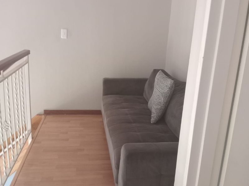 A narrow hallway area featuring laminate flooring and a metal balustrade with a wooden handrail.
